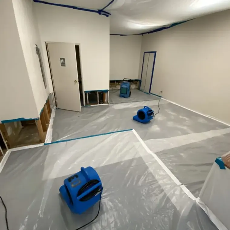 Air movers drying a stripped floor inside plastic containment in Escondido