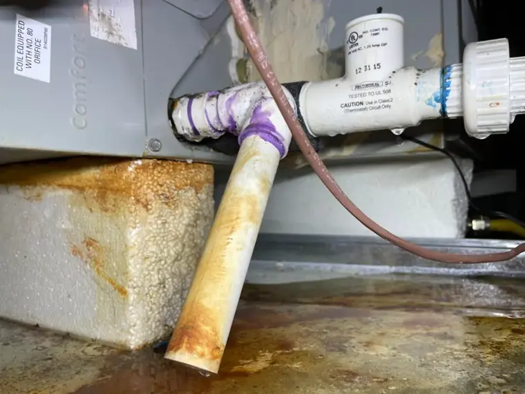 Rusted condensate drain pan under an attic air handler in Escondido