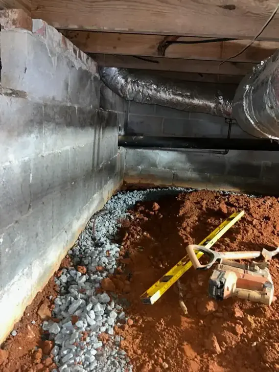 Crawlspace under a raised foundation with ducts and damp soil in Escondido
