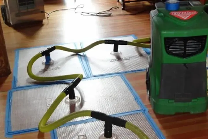 Floor drying mats and hoses pulling moisture out of an Escondido hardwood floor